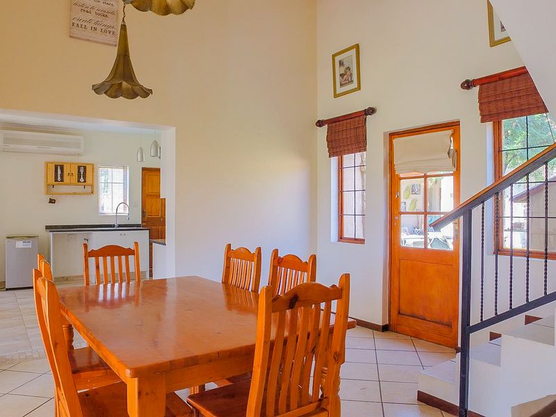 Open plan dining area featuring tiled floors, a staircase, and direct access to the kitchen and outdoor area.