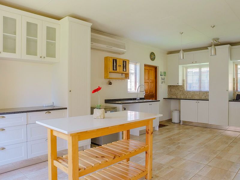 A bright and spacious kitchen featuring white cabinetry, granite countertops, tiled backsplash, and tiled flooring, offering a clean and functional culinary space.