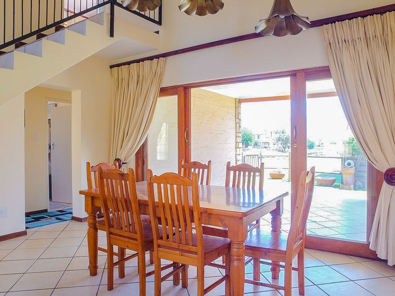 Dining area featuring tiled flooring, a staircase with metal railing, and large sliding glass doors providing access to the outdoor patio.