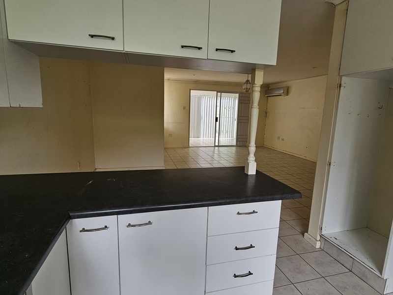 Open plan kitchen and living area featuring tiled floors, built-in cabinetry, and a sliding door leading to the exterior, offering a blank canvas for renovation.