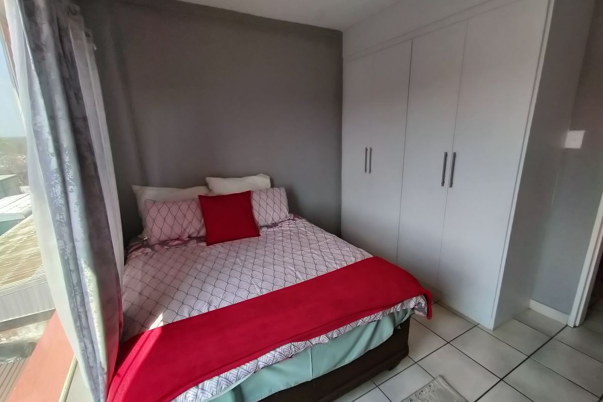 A well-maintained bedroom featuring built-in cupboards and neutral tiled flooring, offering a clean and functional living space.