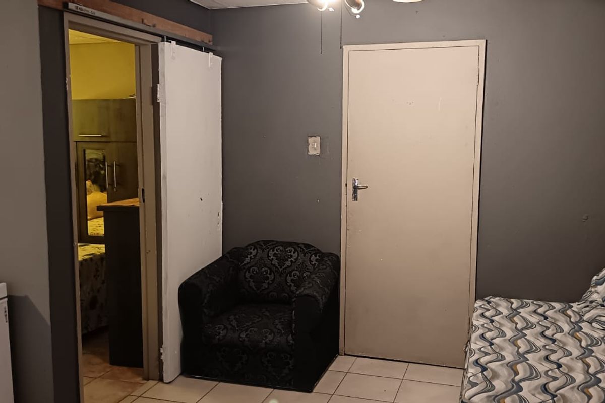 A bedroom featuring tiled flooring, built-in shelving, and access to an adjoining room via a sliding door.