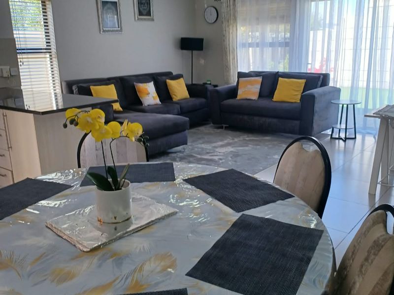 Spacious open-plan living and dining area featuring tiled flooring, modern kitchen cabinetry with an island, and large sliding doors leading to the exterior.