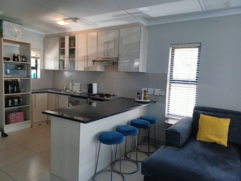Modern open-plan kitchen featuring sleek cabinetry, granite countertops, and a breakfast bar, seamlessly integrated with the living area for a functional, contemporary layout.
