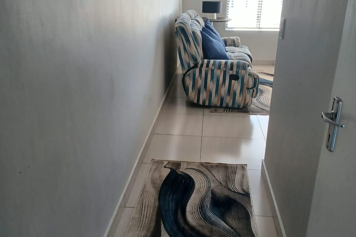 A view from a hallway into a living area featuring tiled flooring and venetian blinds.