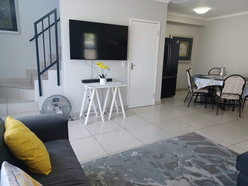 Open plan living and dining area featuring tiled flooring and a staircase with metal railing.