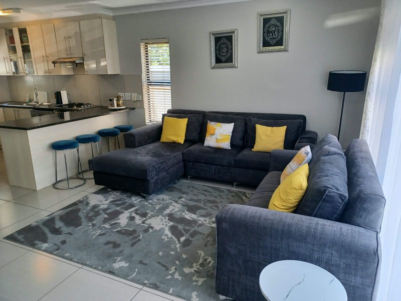 Modern open-plan living area featuring a well-appointed kitchen with granite countertops, gas hob, and sleek cabinetry, seamlessly flowing into a comfortable lounge space.