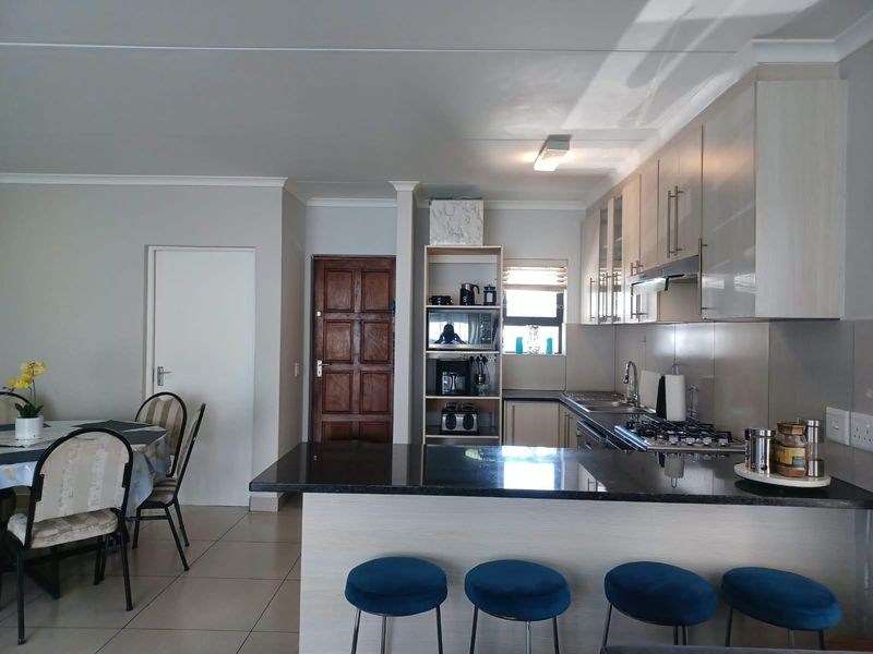 Open-plan kitchen and dining area featuring modern cabinetry, granite countertops, gas hob, and tiled flooring, creating a functional and cohesive living space.
