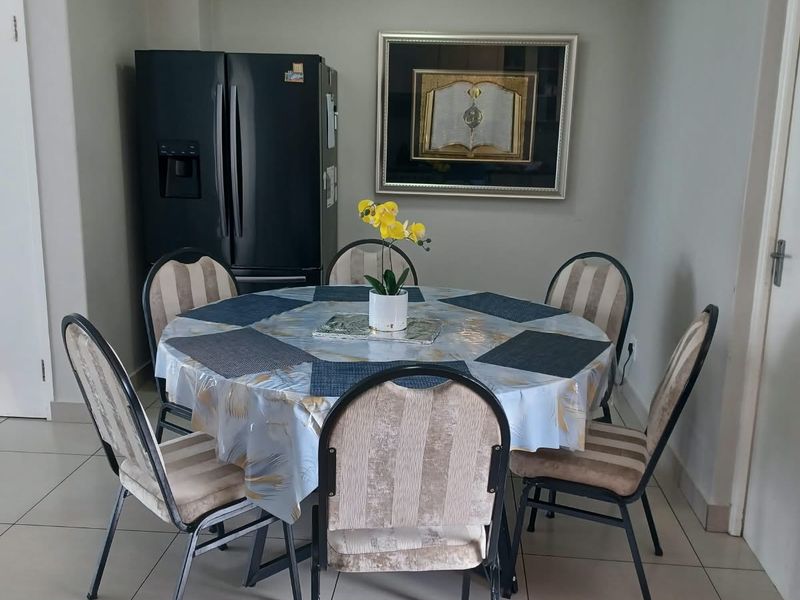 A functional dining area featuring neutral tiled flooring and a coved ceiling, providing a clean and practical space for meals.