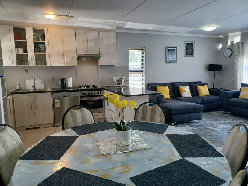 Open-plan living area featuring a functional kitchen with built-in cabinetry, gas hob, and breakfast bar, seamlessly flowing into the adjacent lounge space.