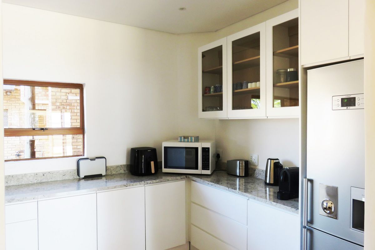 A modern kitchen featuring white cabinetry, granite countertops, and glass-front upper display cabinets, providing a clean and functional workspace.