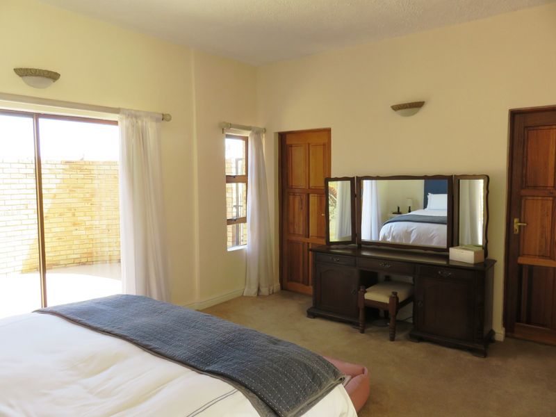Spacious bedroom featuring carpeted flooring, wall-mounted lighting, and direct access to an outdoor patio area through a sliding glass door.