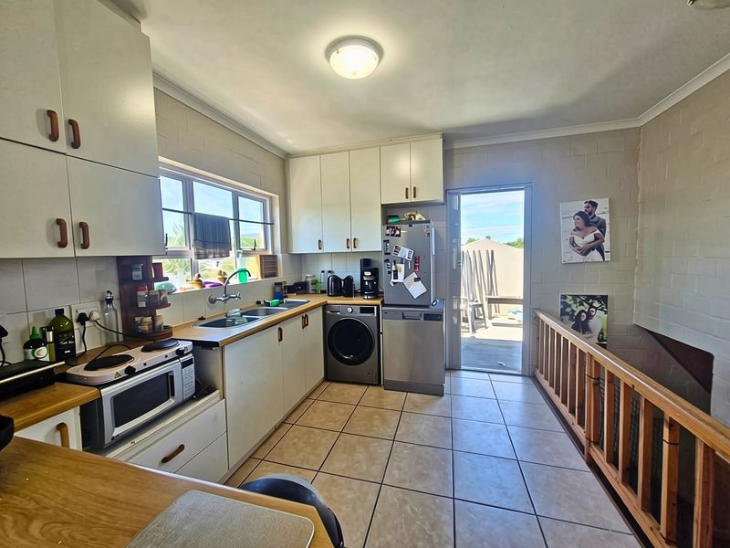 Functional kitchen featuring built-in cabinetry, double basin sink, and tiled flooring, with direct access to an outdoor patio area.