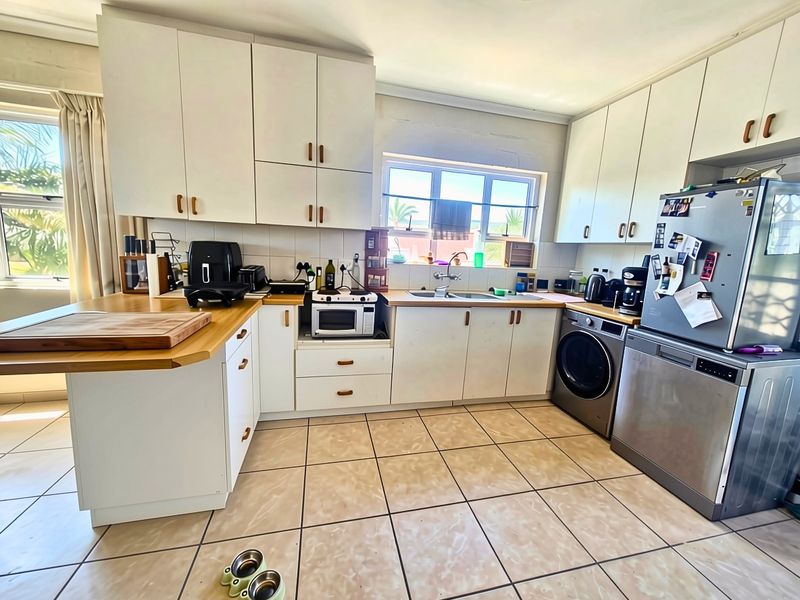 Functional kitchen featuring white built-in cabinetry, laminate countertops, double basin sink, and tiled flooring with a practical layout.