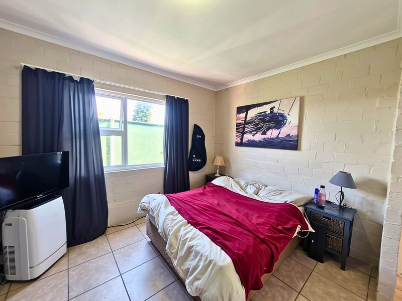 A bedroom featuring tiled flooring and painted brick walls with a large window providing natural light.