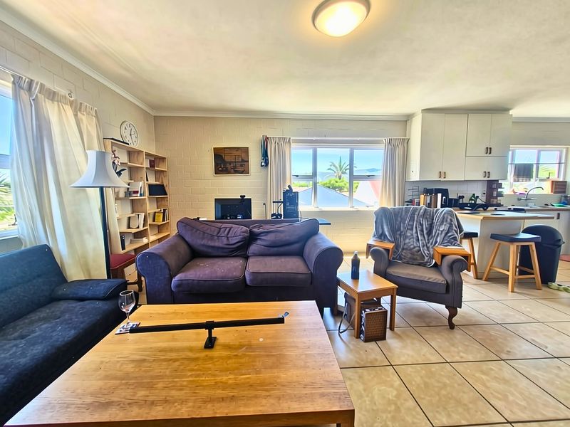 Open plan living and kitchen area featuring tiled flooring, exposed blockwork walls, and functional kitchen cabinetry with an island bench.