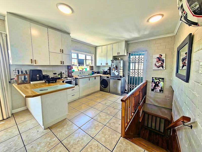 Functional kitchen featuring built-in cabinetry, wooden countertops, and tiled flooring, with an adjacent staircase leading to another level.