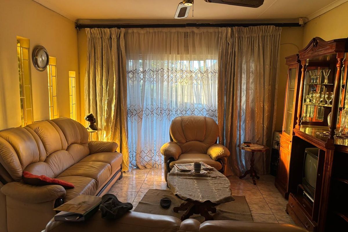A cozy living room featuring tiled flooring, a ceiling fan, and a large sliding glass door that allows for natural light.