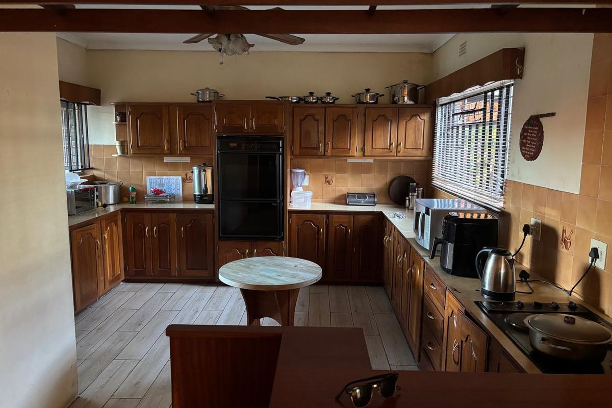 A functional kitchen featuring traditional wooden cabinetry, built-in oven, ceramic tile backsplash, and wood-look flooring, offering a classic layout with ample storage space.