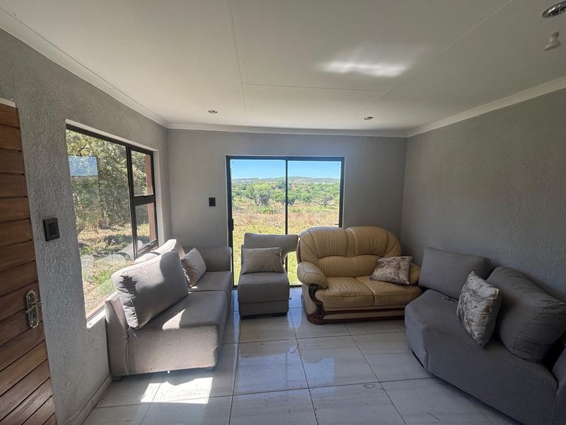 A bright living room featuring large windows and sliding glass doors that provide natural light and scenic views of the surrounding landscape.