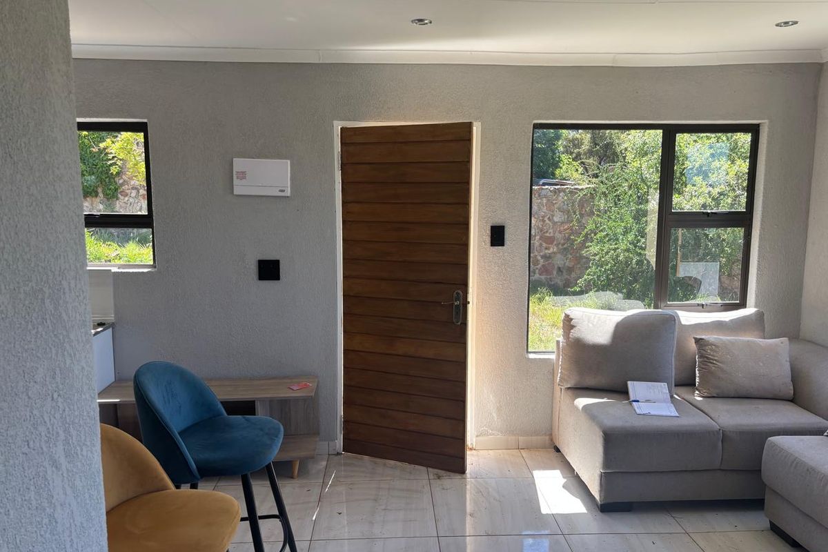 A bright living area featuring tiled flooring, recessed lighting, and direct access to the exterior through a timber door.