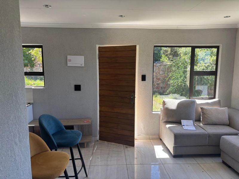 A bright living area featuring tiled flooring, recessed lighting, and direct access to the exterior through a timber door.
