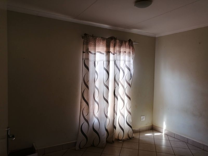 A vacant bedroom featuring tiled flooring, neutral wall finishes, and a ceiling light fixture, offering a blank canvas for potential interior updates.