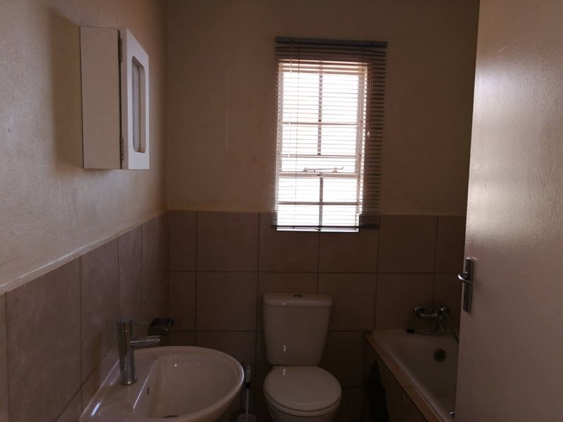 A functional bathroom featuring a pedestal basin, toilet, and bathtub with tiled splashbacks and a wall-mounted medicine cabinet.