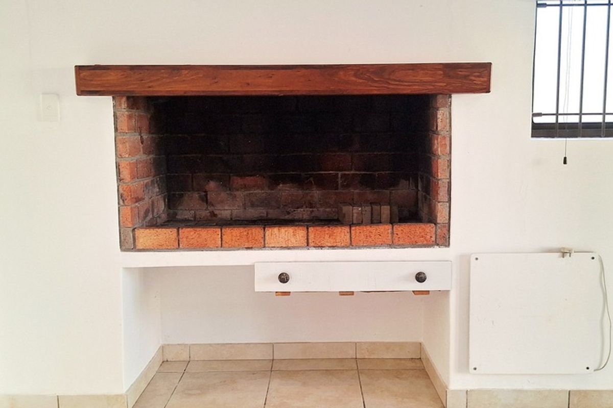 Indoor built-in brick fireplace with a wooden mantelpiece, tiled flooring, and security gate access to the exterior.