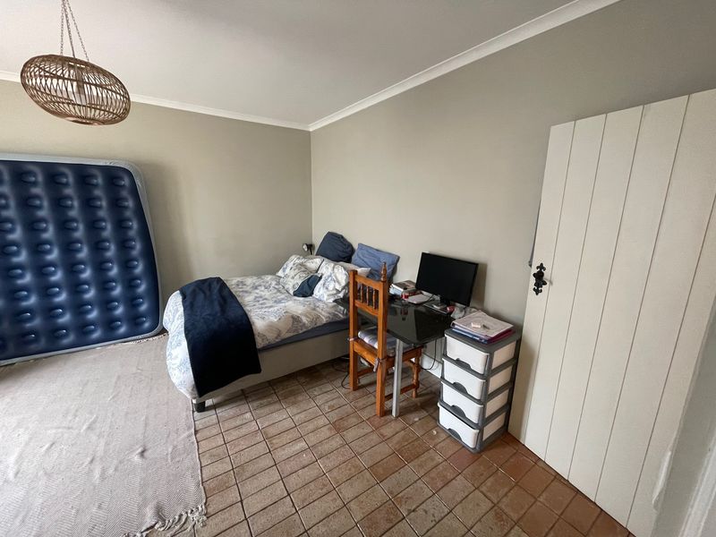 A bedroom featuring tiled flooring, neutral wall paint, and a classic timber door, offering a functional space ready for personalization.