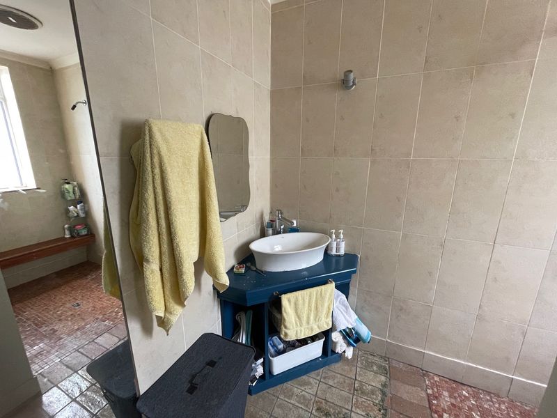 Bathroom featuring a vessel sink, large wall mirror, and tiled finishes with a built-in shower bench area.
