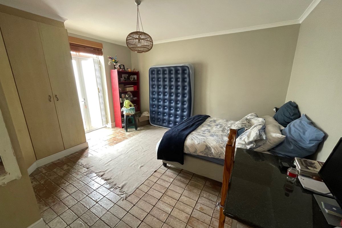 A bedroom featuring built-in cupboards, tiled flooring, and direct access to an outdoor area through a glass paneled door.
