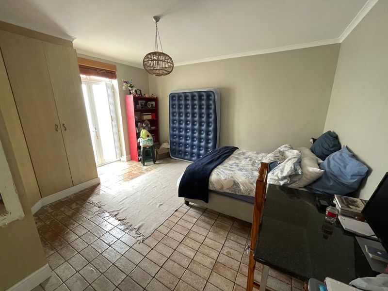 A bedroom featuring built-in cupboards, tiled flooring, and direct access to an outdoor area through a glass paneled door.