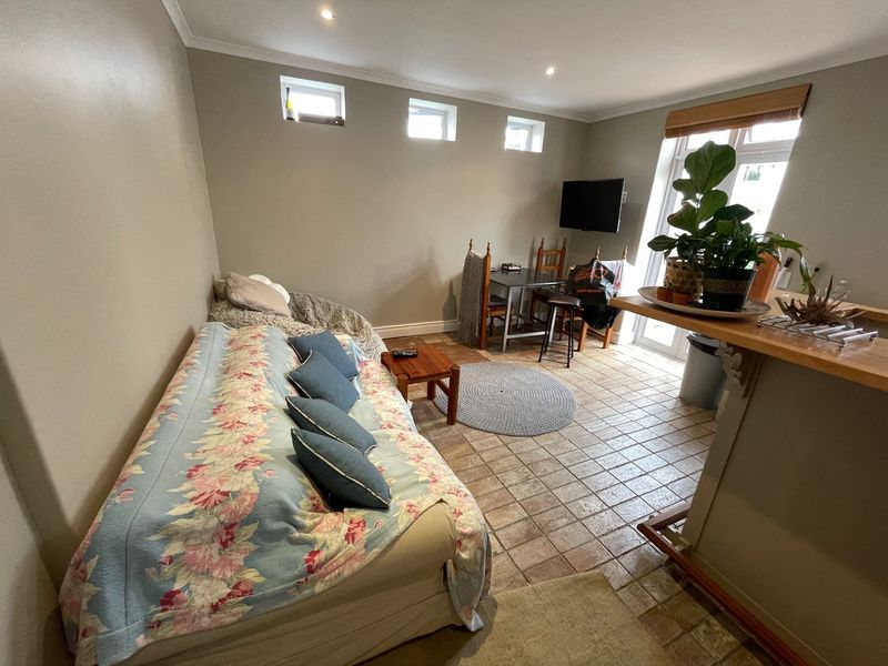Open plan living area featuring tiled flooring, recessed lighting, and a breakfast bar, with direct access to an outdoor space through a glass door.