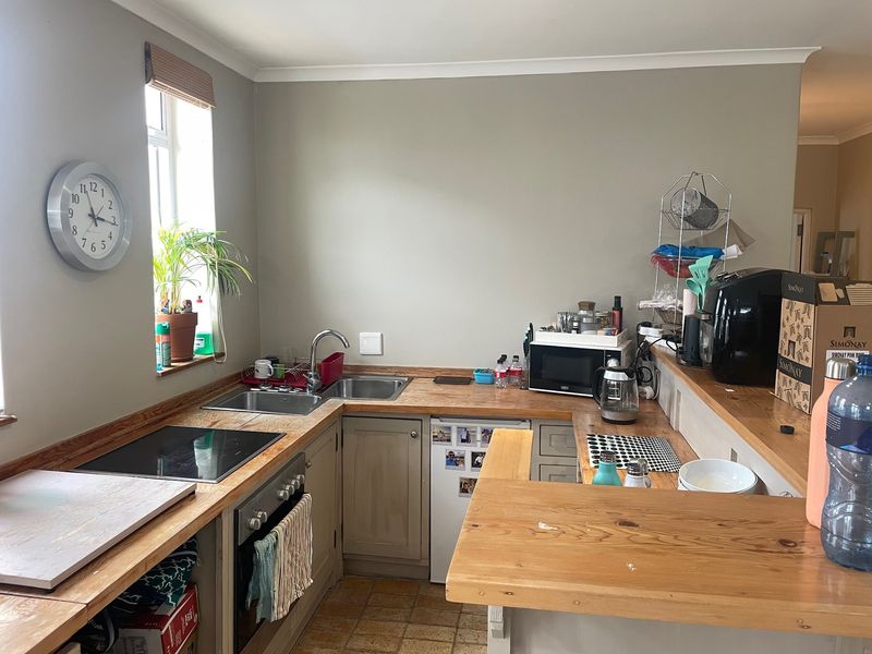 A functional kitchen featuring wooden countertops, built-in oven, electric hob, and a breakfast bar, offering a practical layout for daily use.