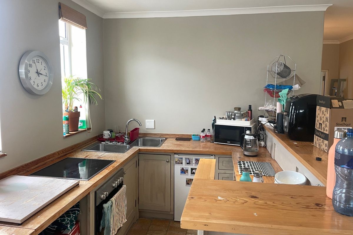 A functional kitchen featuring wooden countertops, built-in oven, electric hob, and a breakfast bar, offering a practical layout for daily use.