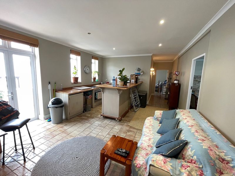 Open-plan living and kitchen area featuring tiled flooring, a central kitchen island with wooden countertops, and direct access to an outdoor space.