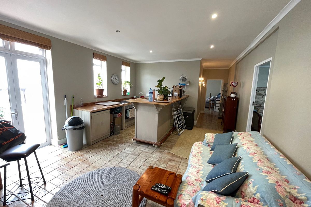 Open-plan living and kitchen area featuring tiled flooring, a central kitchen island with wooden countertops, and direct access to an outdoor space.