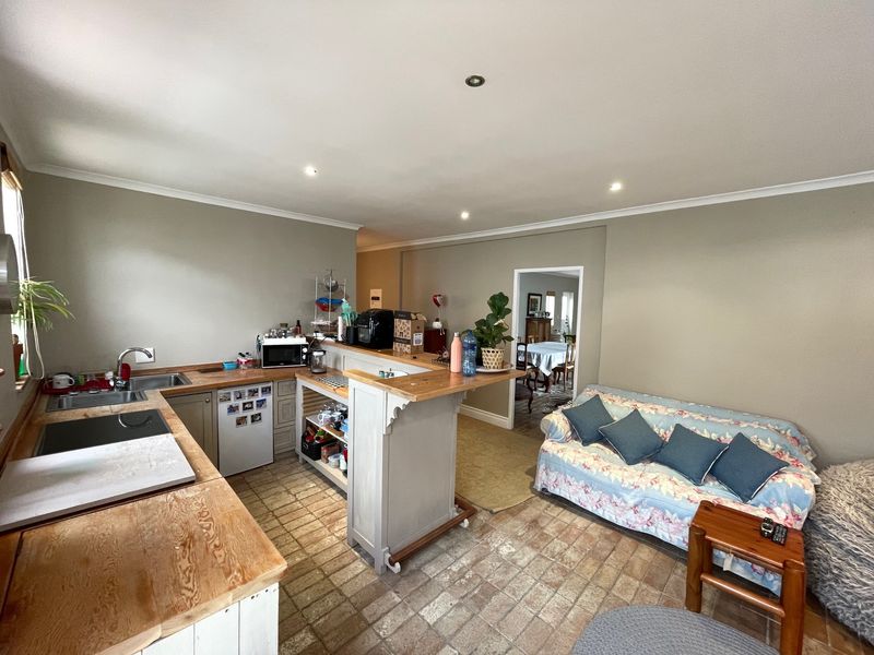 Open-plan kitchen and living area featuring wooden countertops, a breakfast bar, and tiled flooring, creating a functional and connected living space.