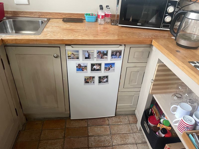 A compact kitchen area featuring wooden countertops, built-in cabinetry, and tiled flooring, offering a functional space with potential for cosmetic updates.