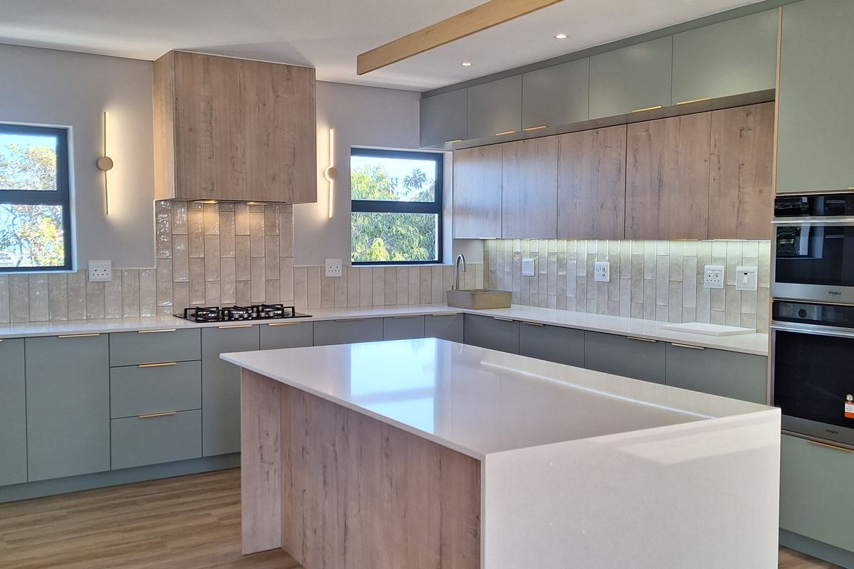 Modern kitchen featuring a central island, stone countertops, integrated oven and microwave, and stylish cabinetry with under-cabinet lighting.