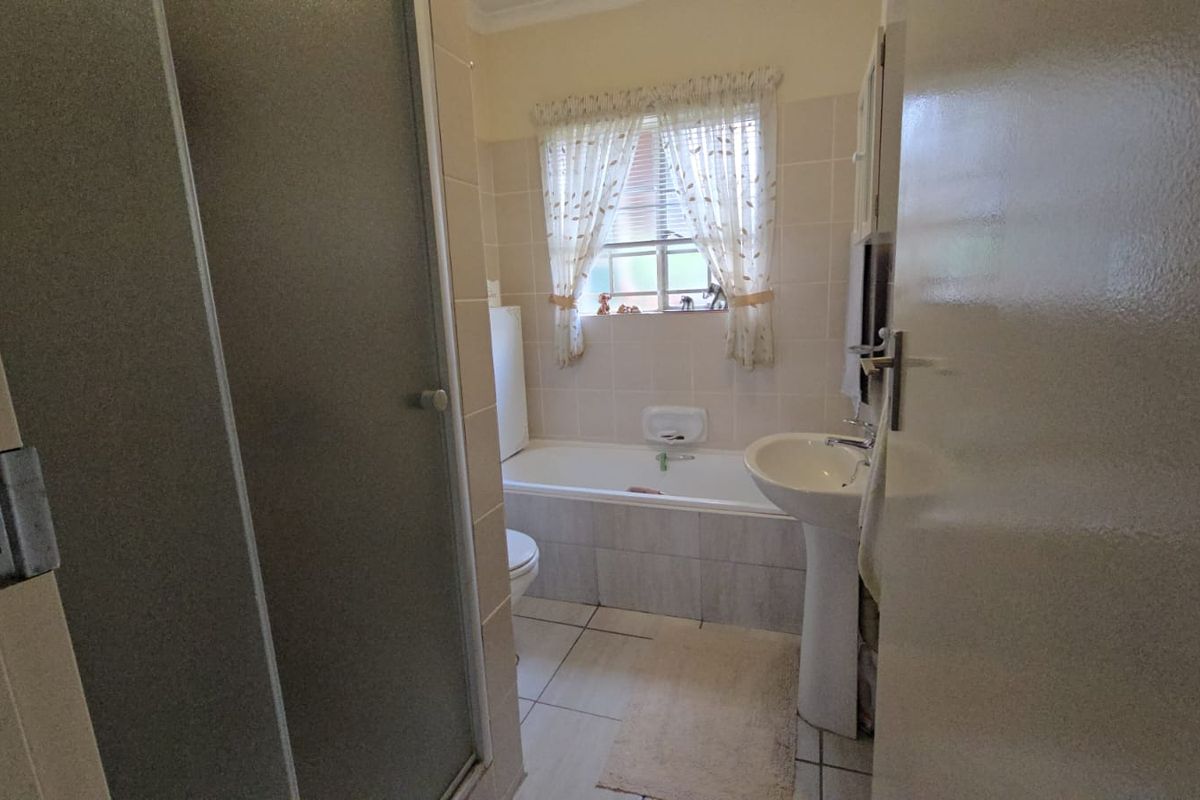 A functional bathroom featuring a pedestal basin, a built-in bathtub, and a separate shower enclosure with tiled walls and flooring.