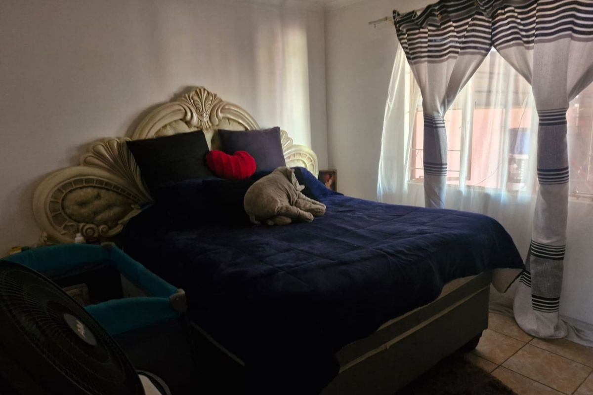 A bedroom featuring tiled flooring and a window with curtain treatments.