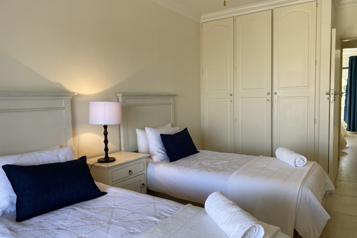 A bedroom featuring built-in cupboards with classic panel detailing and tiled flooring, offering a functional and neutral living space.