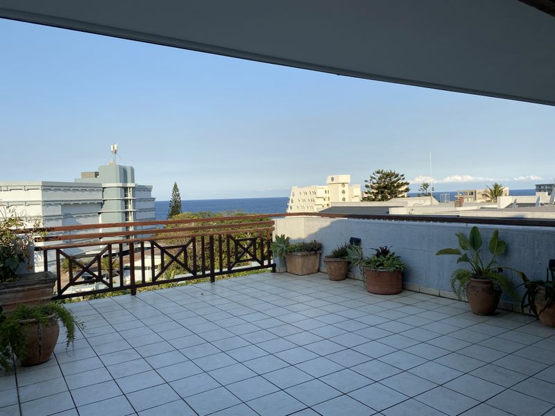 Spacious balcony featuring tiled flooring, a wooden balustrade, and expansive ocean views, offering a perfect setting for outdoor relaxation.