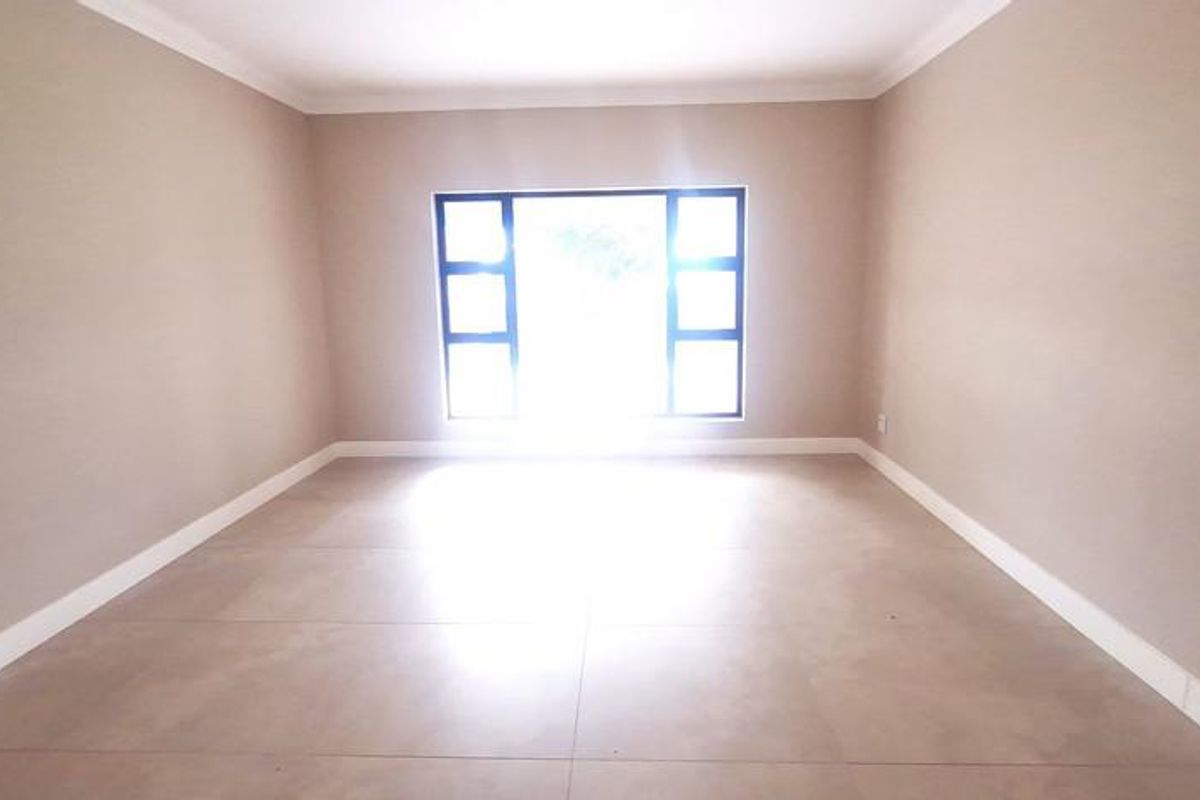 A bright, empty bedroom featuring neutral wall paint, large window, and tiled flooring, providing a clean and versatile space.