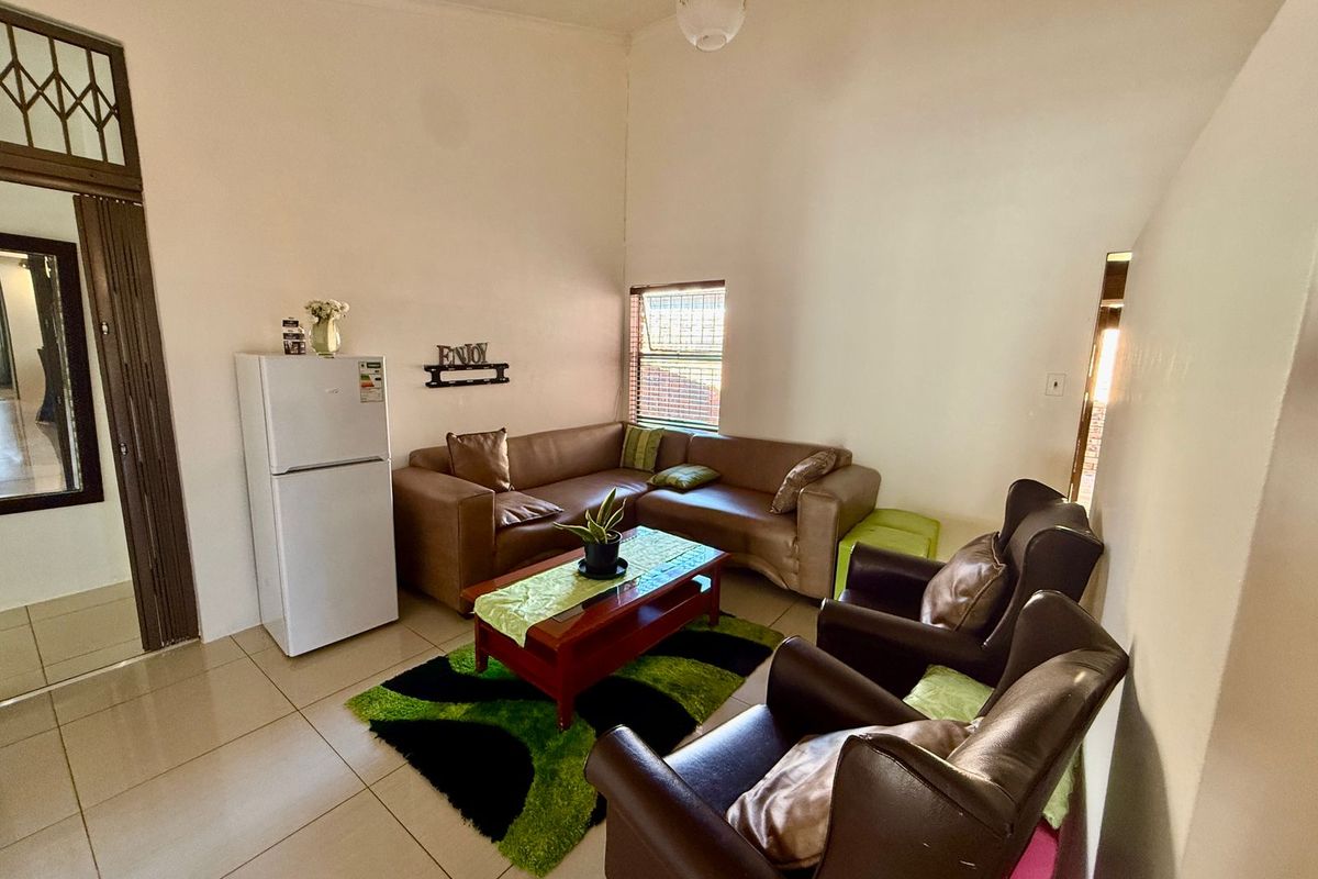 A living room featuring tiled flooring, high ceilings, and a security gate at the entrance.