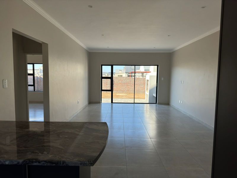 Spacious open-plan living area featuring neutral walls, large sliding glass doors leading to the rear garden, and modern tiled flooring throughout.