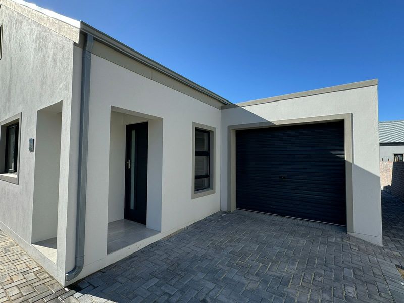 Modern front facade featuring a paved driveway, integrated roller garage door, and clean architectural lines with neutral exterior finishes.