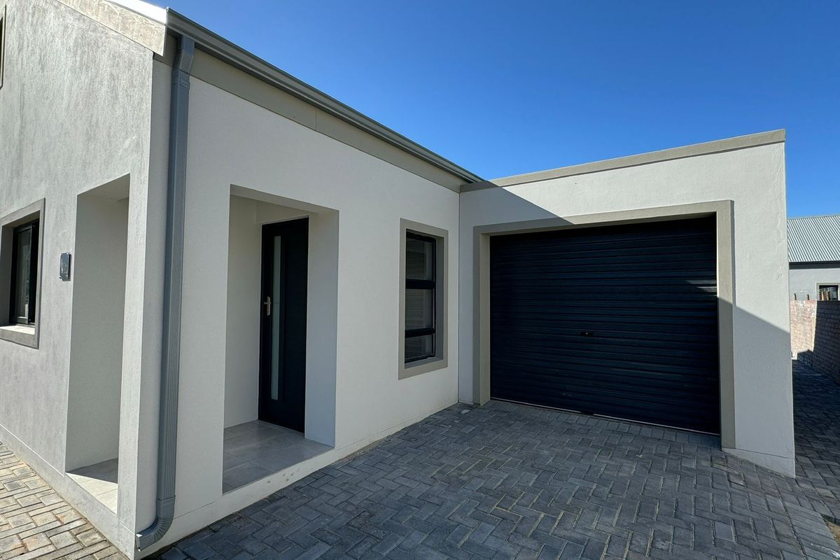 Modern front facade featuring a paved driveway, integrated roller garage door, and clean architectural lines with neutral exterior finishes.